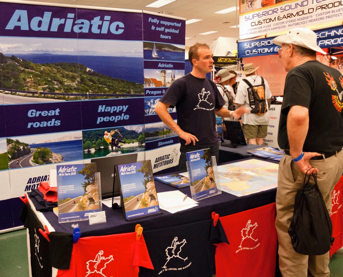 P1020018.jpg - There were a couple of hundred vendors in the conference buildings. Here's BMW o\Outrider member Matej Malovrh at his Adriatic Moto Tours booth.